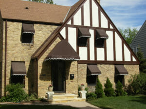 Window and hip style awnings with white scalloped stencil accentuate this lovely Minnesota home